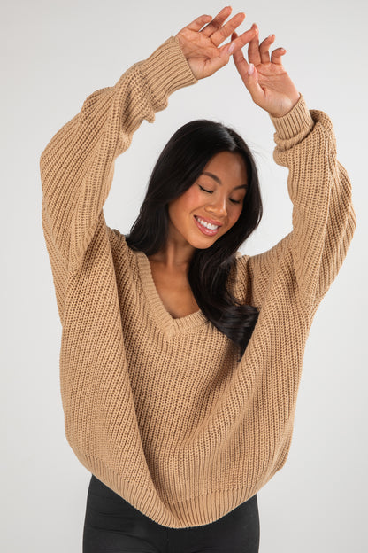 Woman wearing a beige sweater against a white background