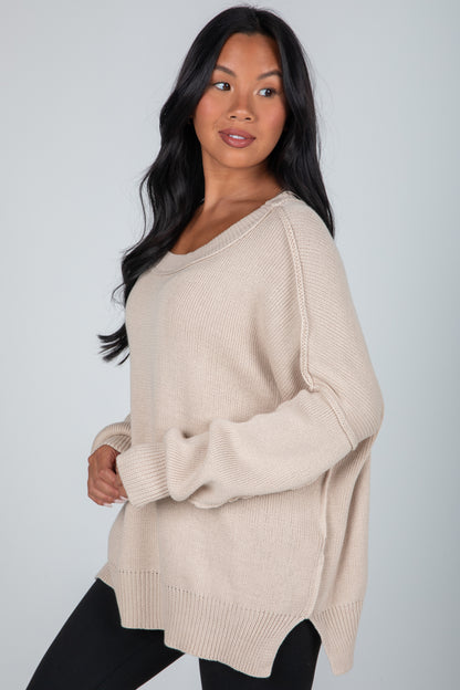 Woman wearing a beige sweater against a plain background