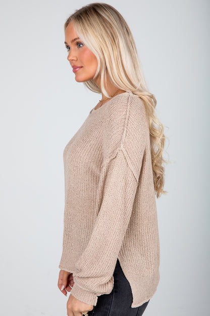Woman wearing a beige sweater against a plain background