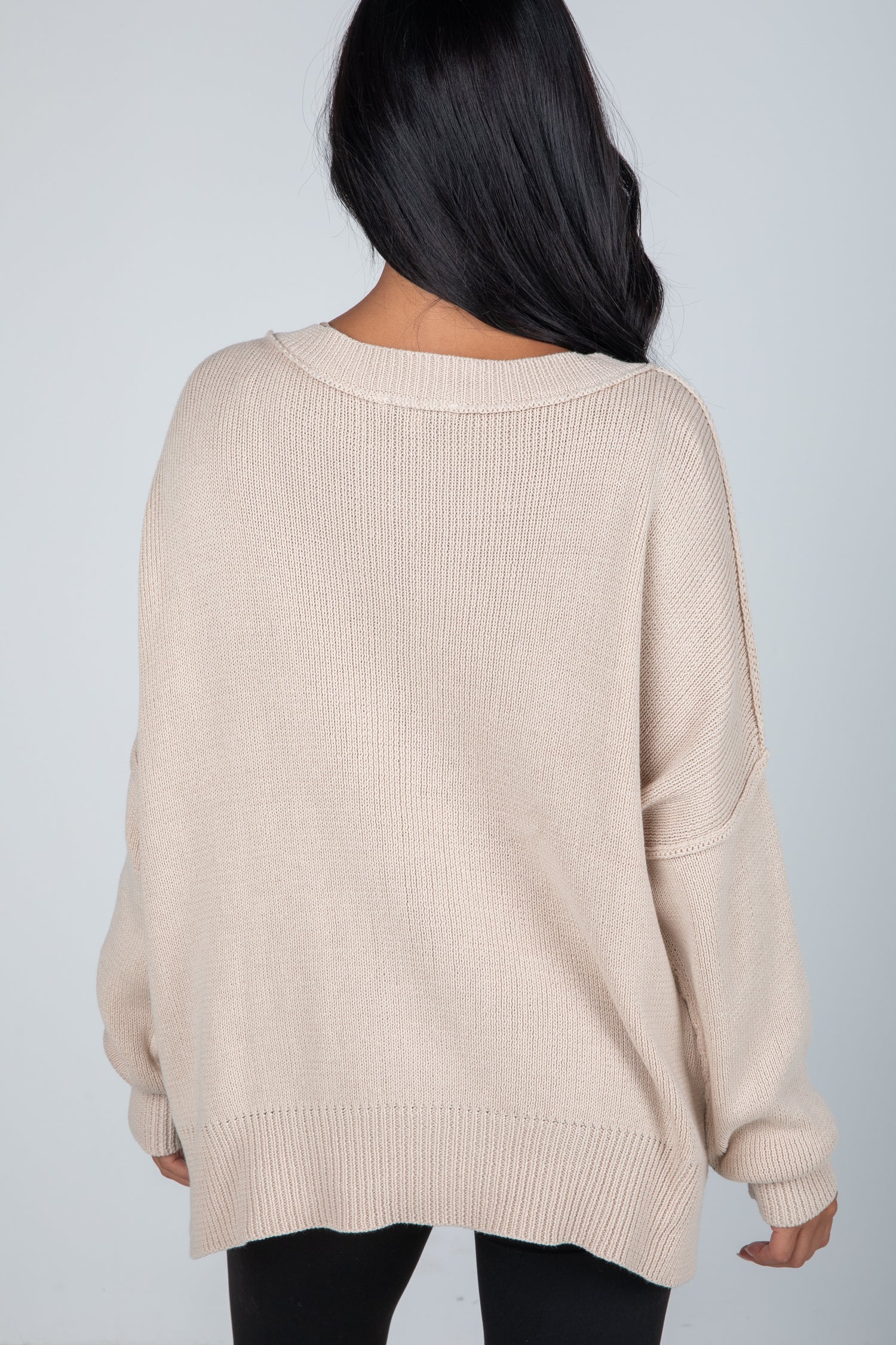 Beige sweater worn by a person on a plain background