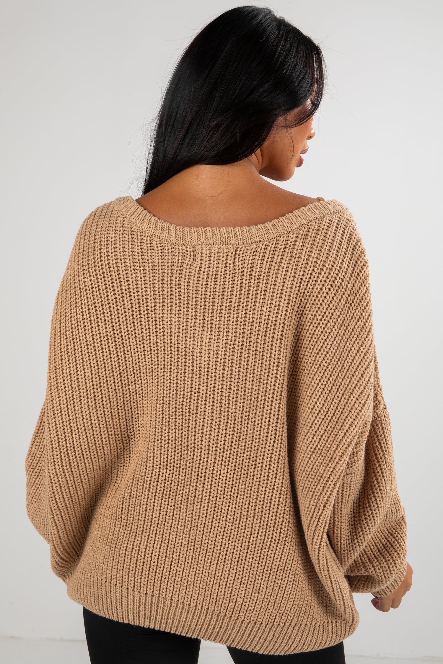 Woman wearing a beige knitted sweater against a white background