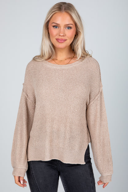 Woman wearing a beige sweater against a plain background