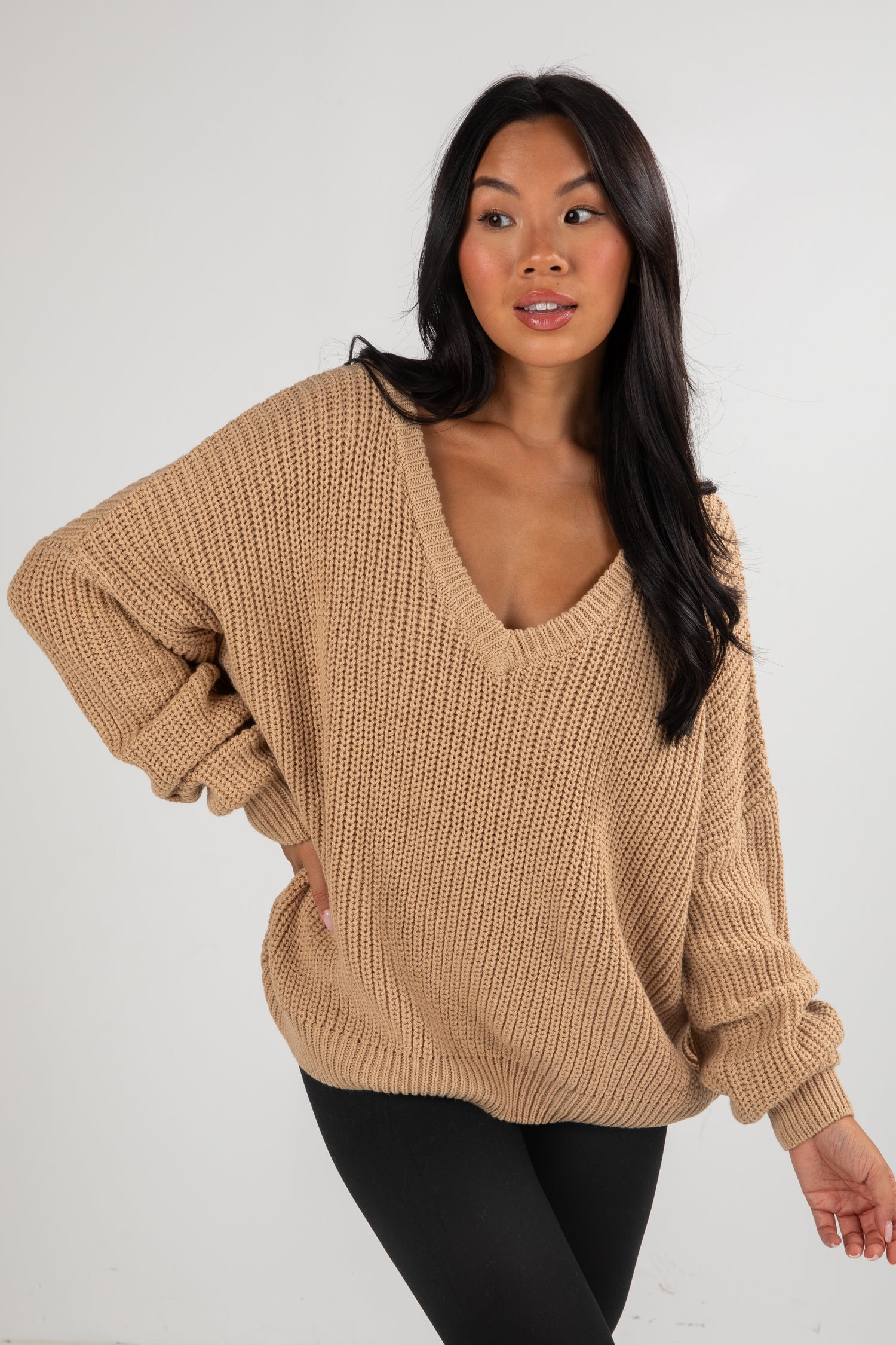Woman wearing a beige sweater against a white background