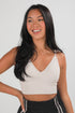 Woman wearing a beige tank top against a plain background