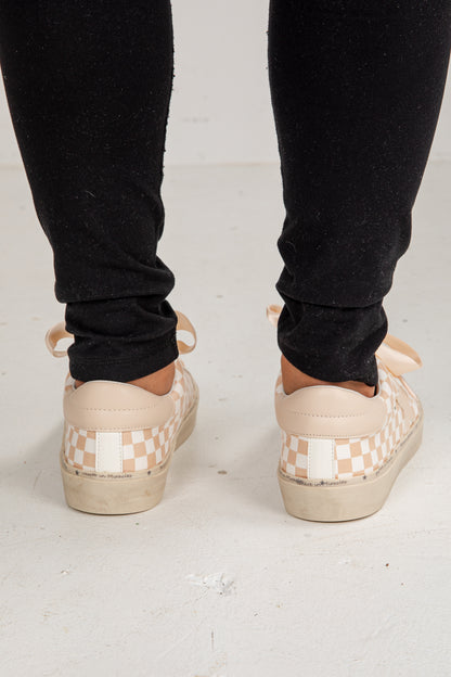 Person wearing checkered platform shoes with black pants on a light background