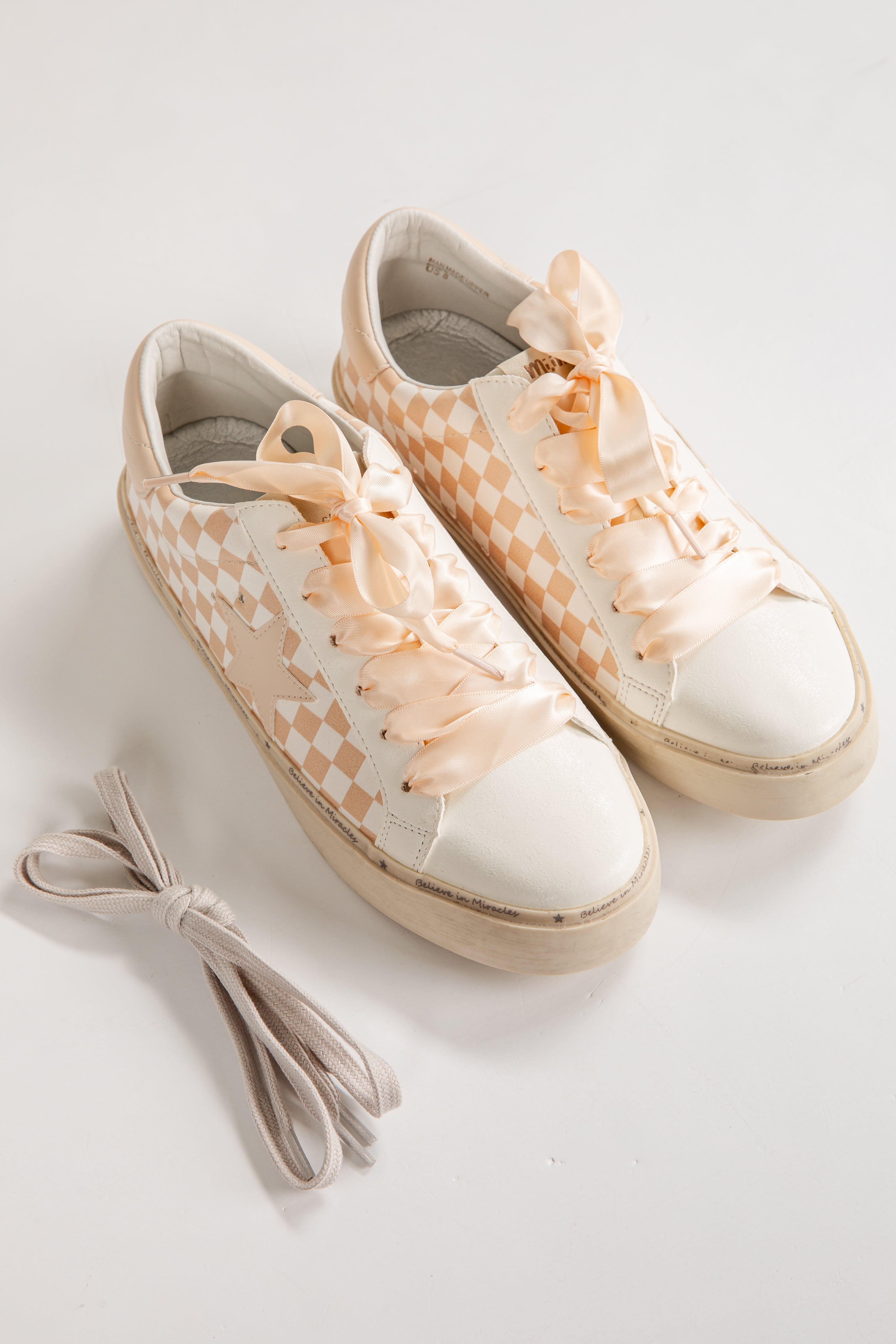 Pair of white sneakers with floral details on a light gray background