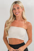 Woman wearing a beige strapless top against a plain background