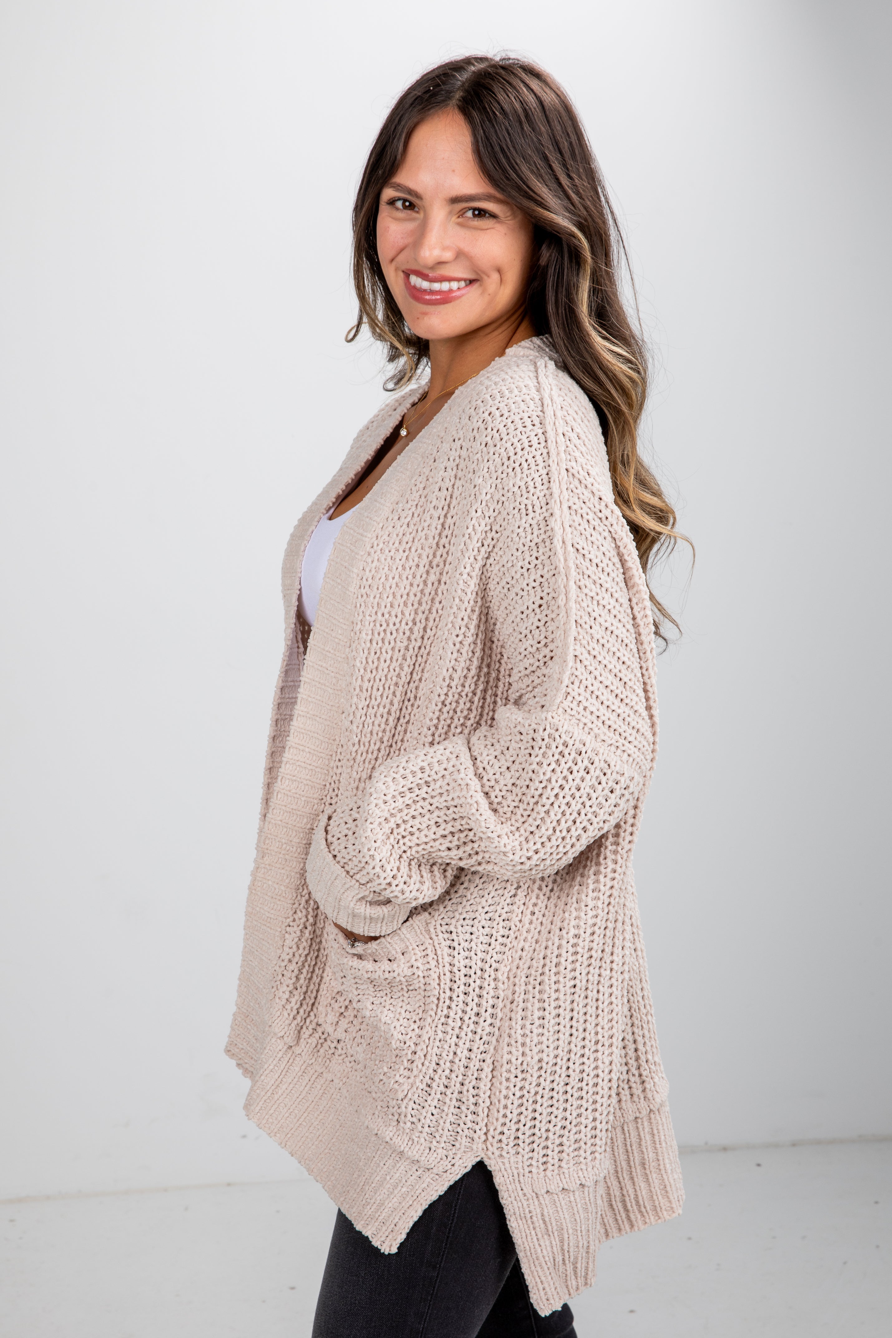 Woman wearing a beige knitted cardigan against a white background