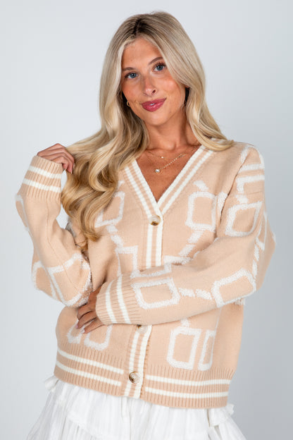 Woman wearing a beige cardigan with geometric pattern on a white background