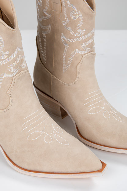 Beige cowboy boots with white embroidery on a white background