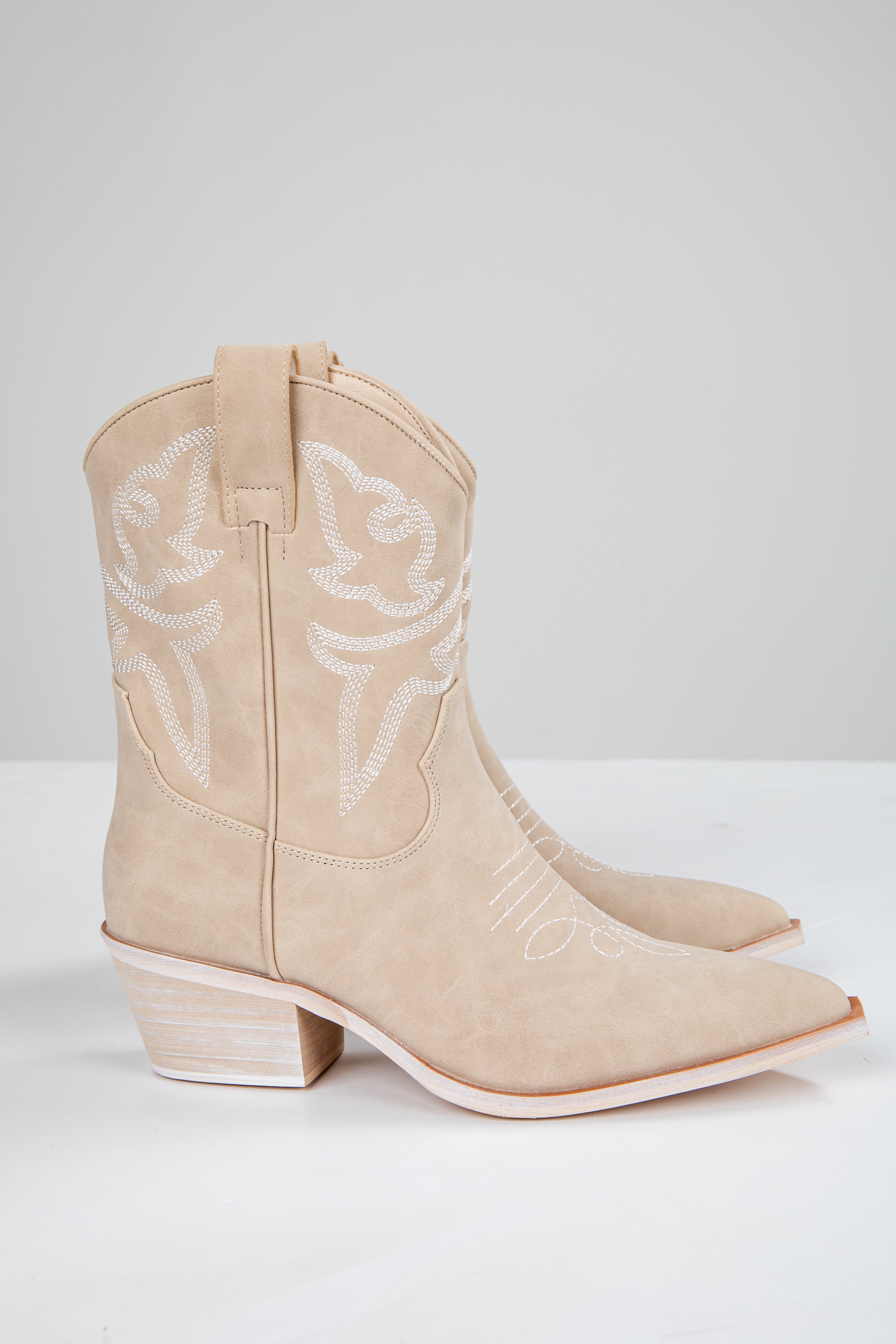 Beige cowboy boots with intricate detailing on a white background