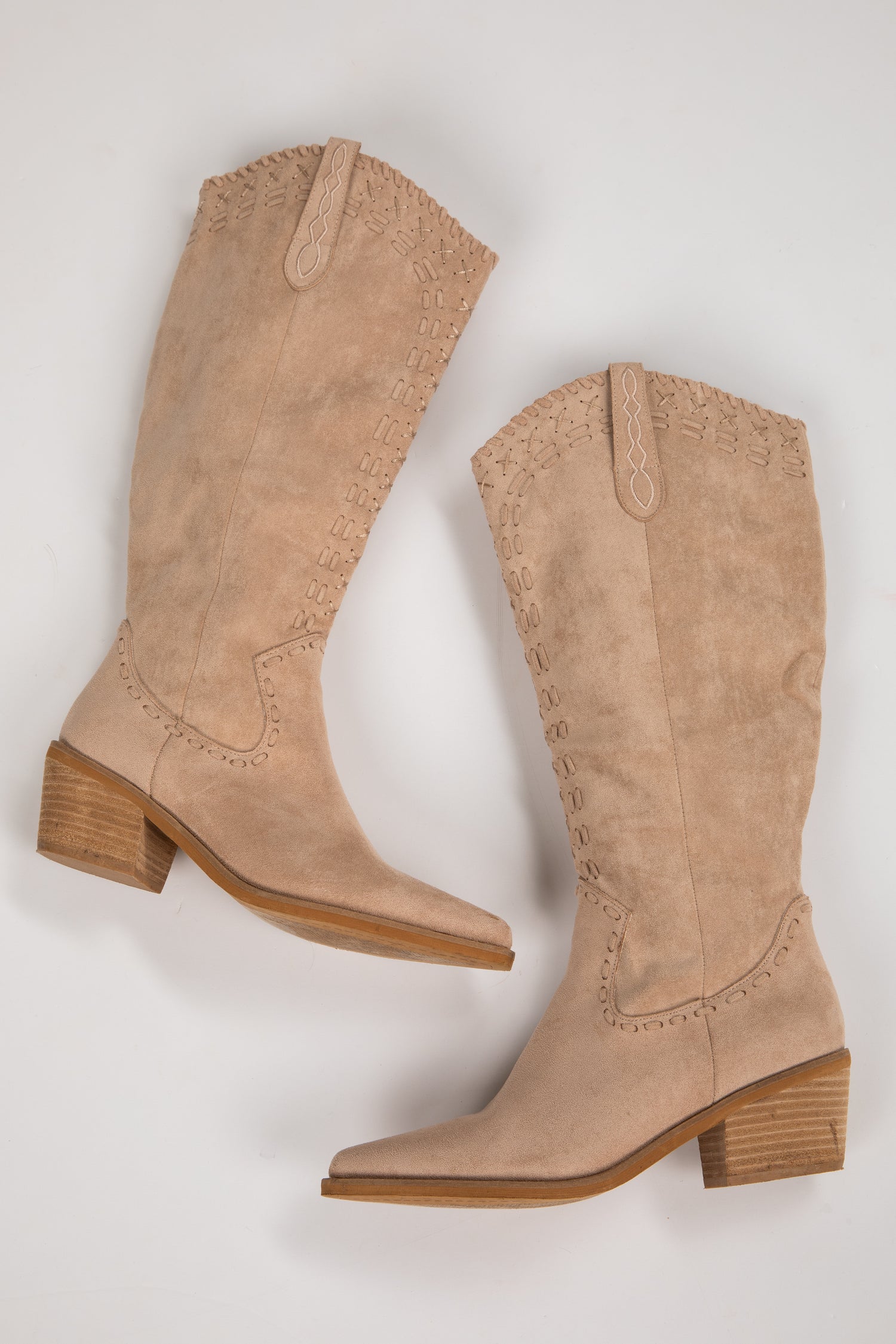 Pair of beige knee-high boots on a light gray background