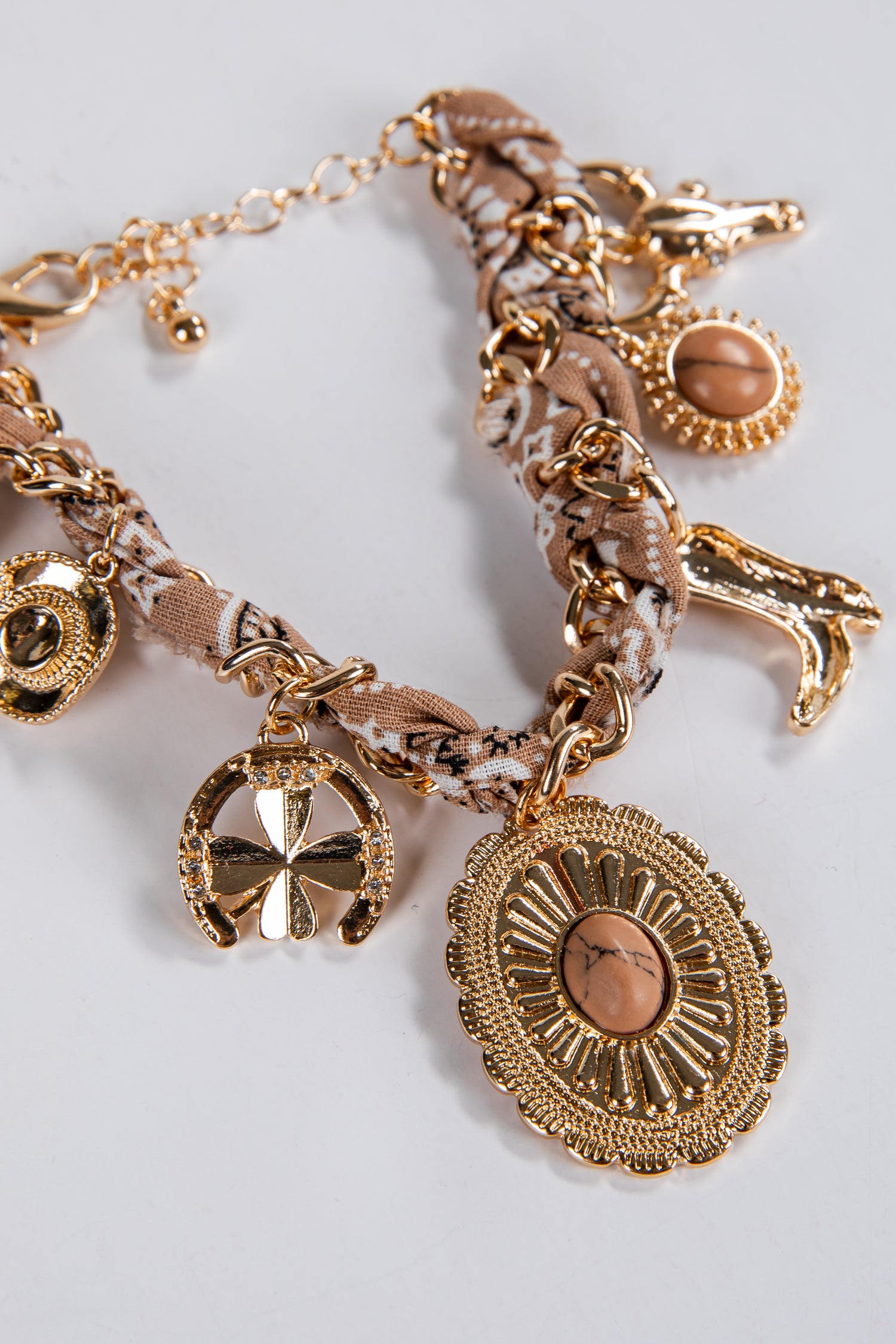 Gold charm bracelet with various charms on a light gray background