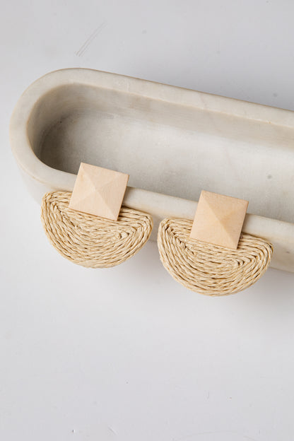 Pair of beige earrings on a white tray with a light gray background