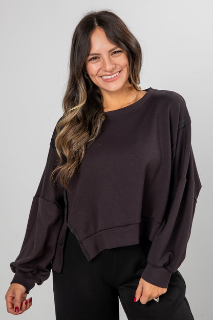 Woman wearing a dark brown oversized sweater against a plain background