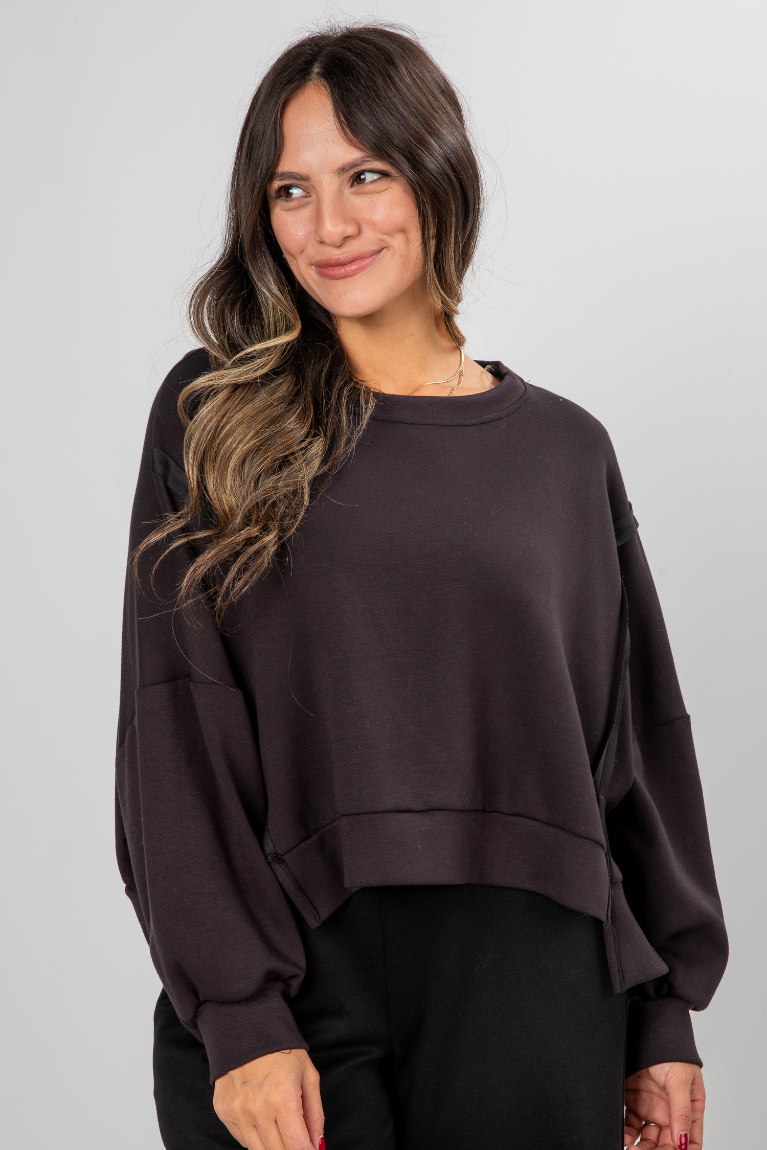 Woman wearing a dark brown oversized sweatshirt against a plain background