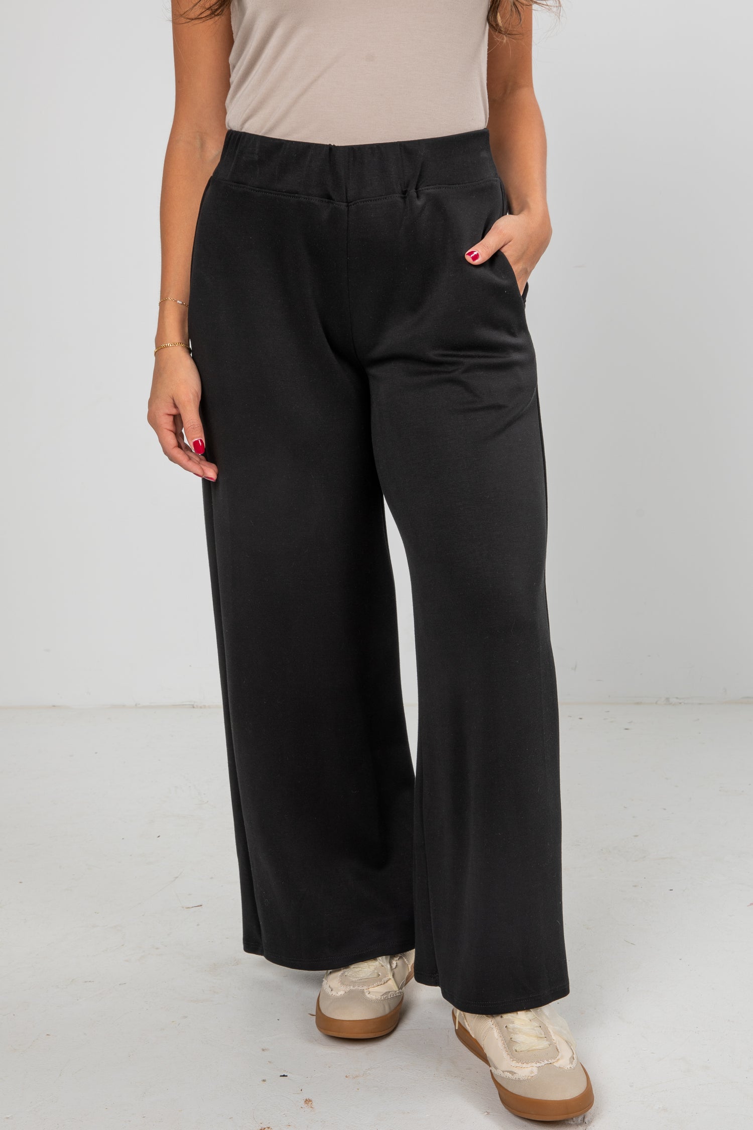 Person wearing black wide-leg pants on a white background
