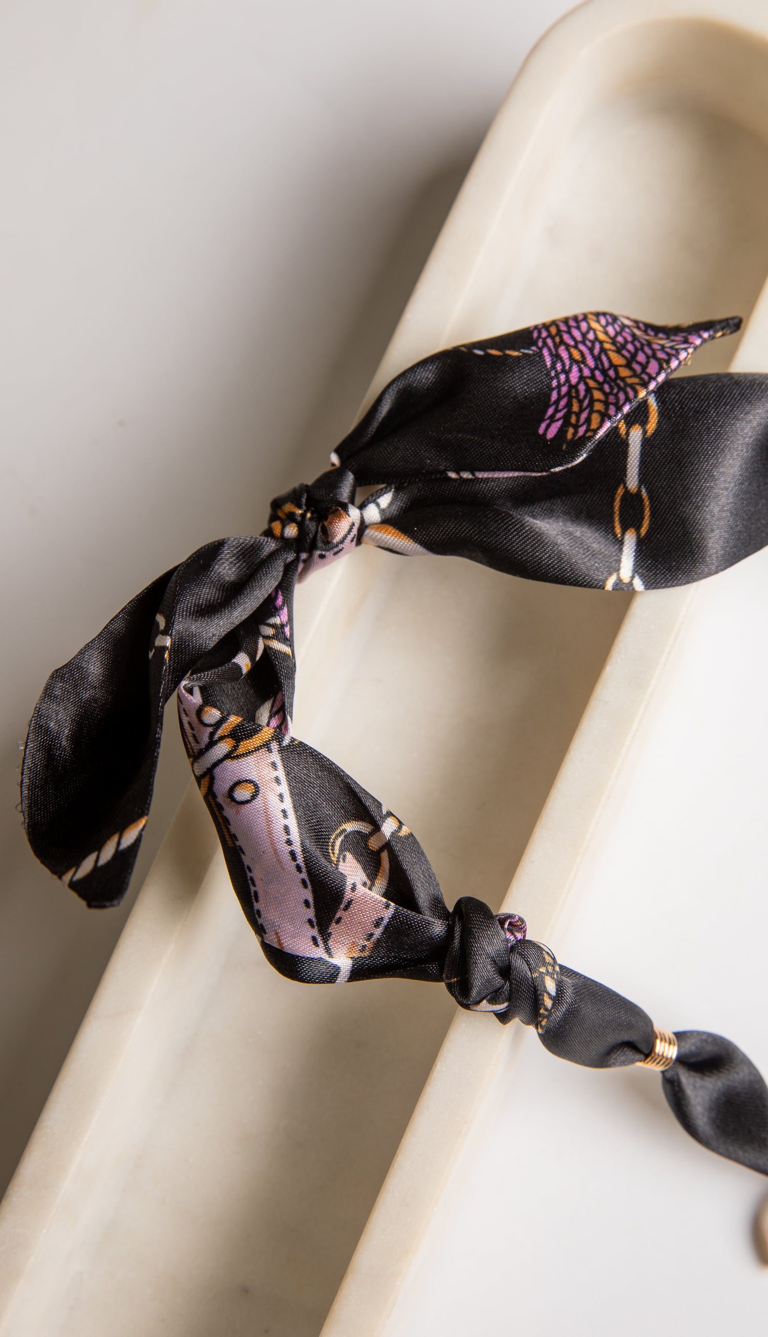 Black hair scrunchie with colorful pattern on a white background