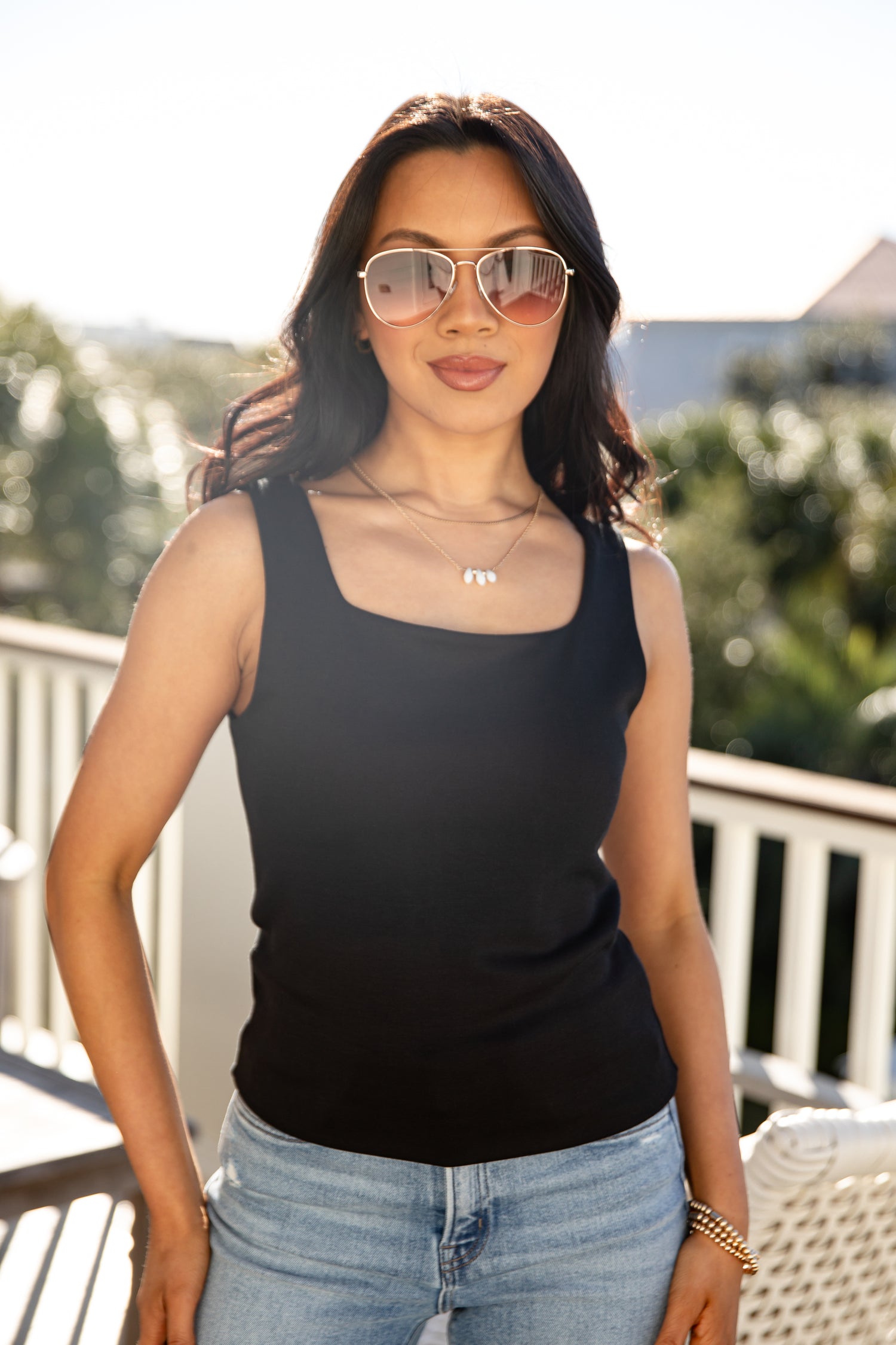 Woman wearing a black tank top and sunglasses outdoors