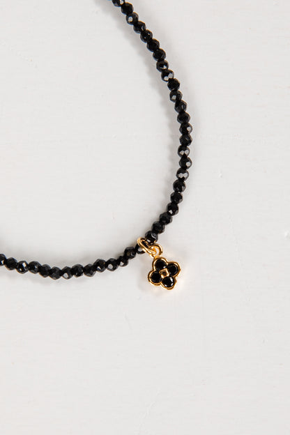 Black beaded necklace with a gold clasp on a white background