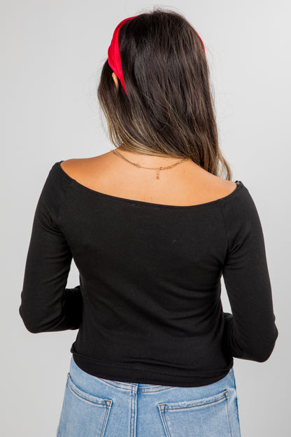 Woman wearing a black long-sleeve top and blue jeans with a red headband on a gray background