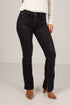 A model wearing black denim jeans with a subtle flare at the ankles, styled with a white ribbed long-sleeve top and brown suede ankle boots against a plain light gray studio background.