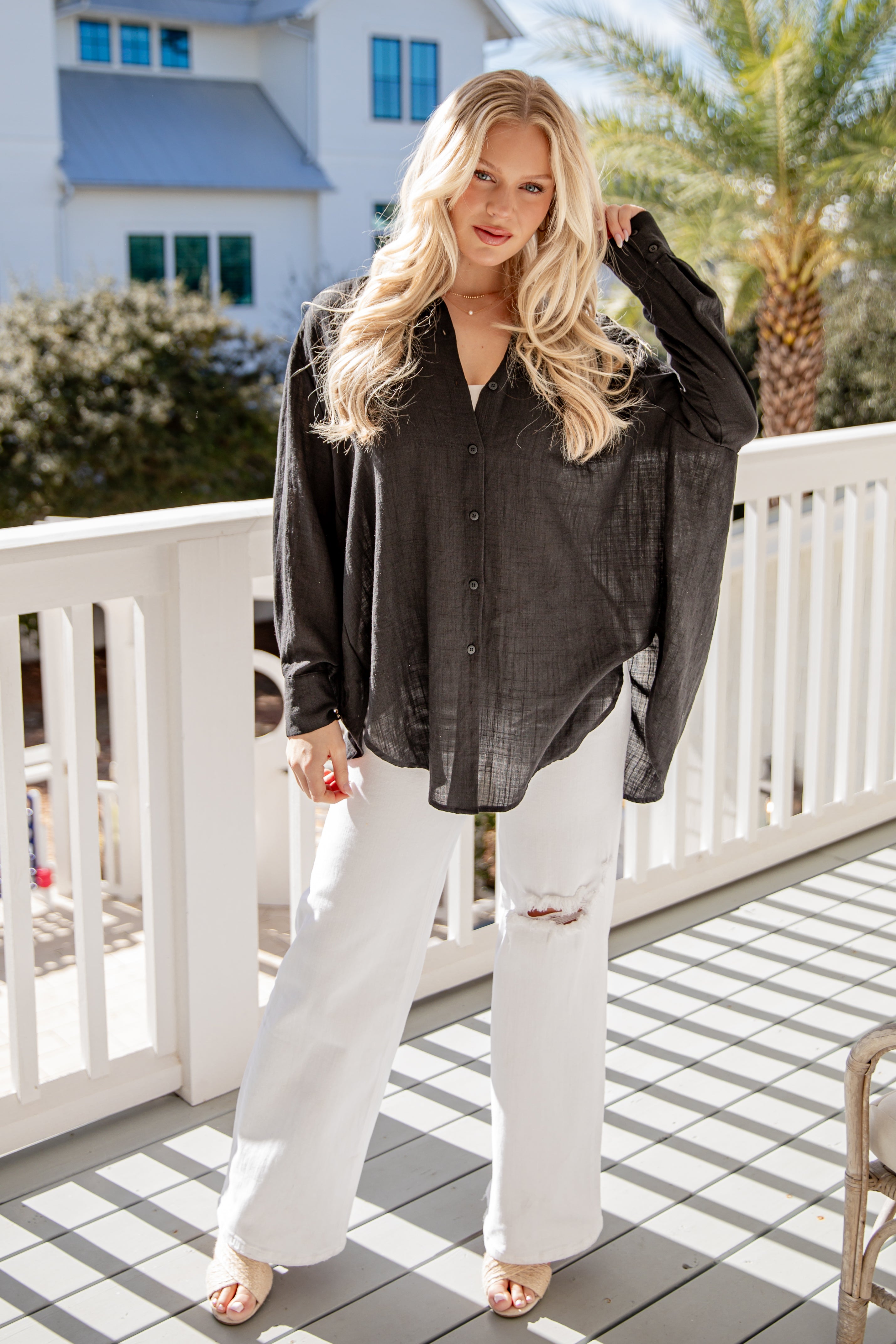 Woman wearing a black shirt and white pants on a balcony