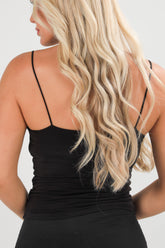 Woman wearing a black tank top with thin straps against a neutral background