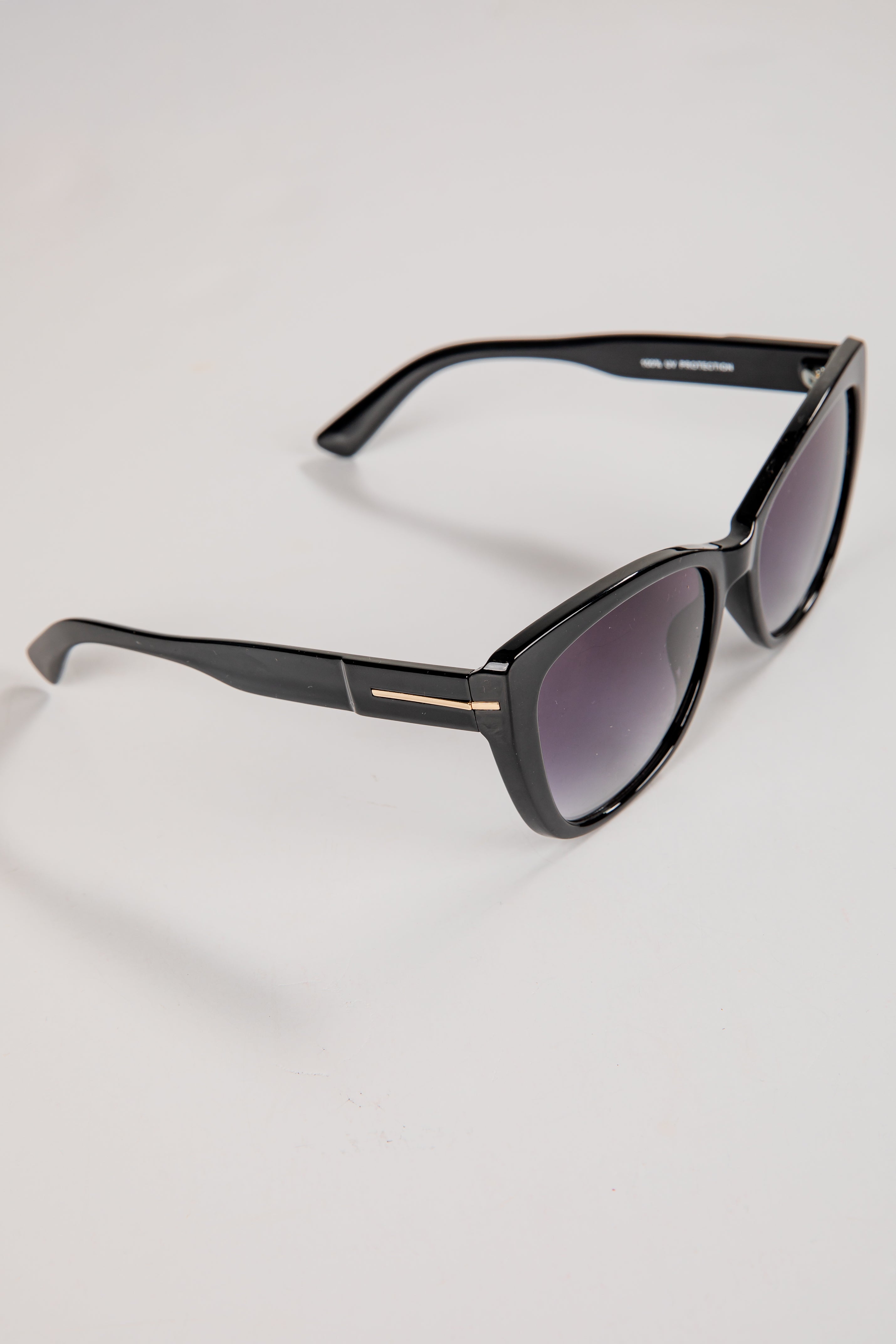 Black sunglasses with a gold accent on a white background