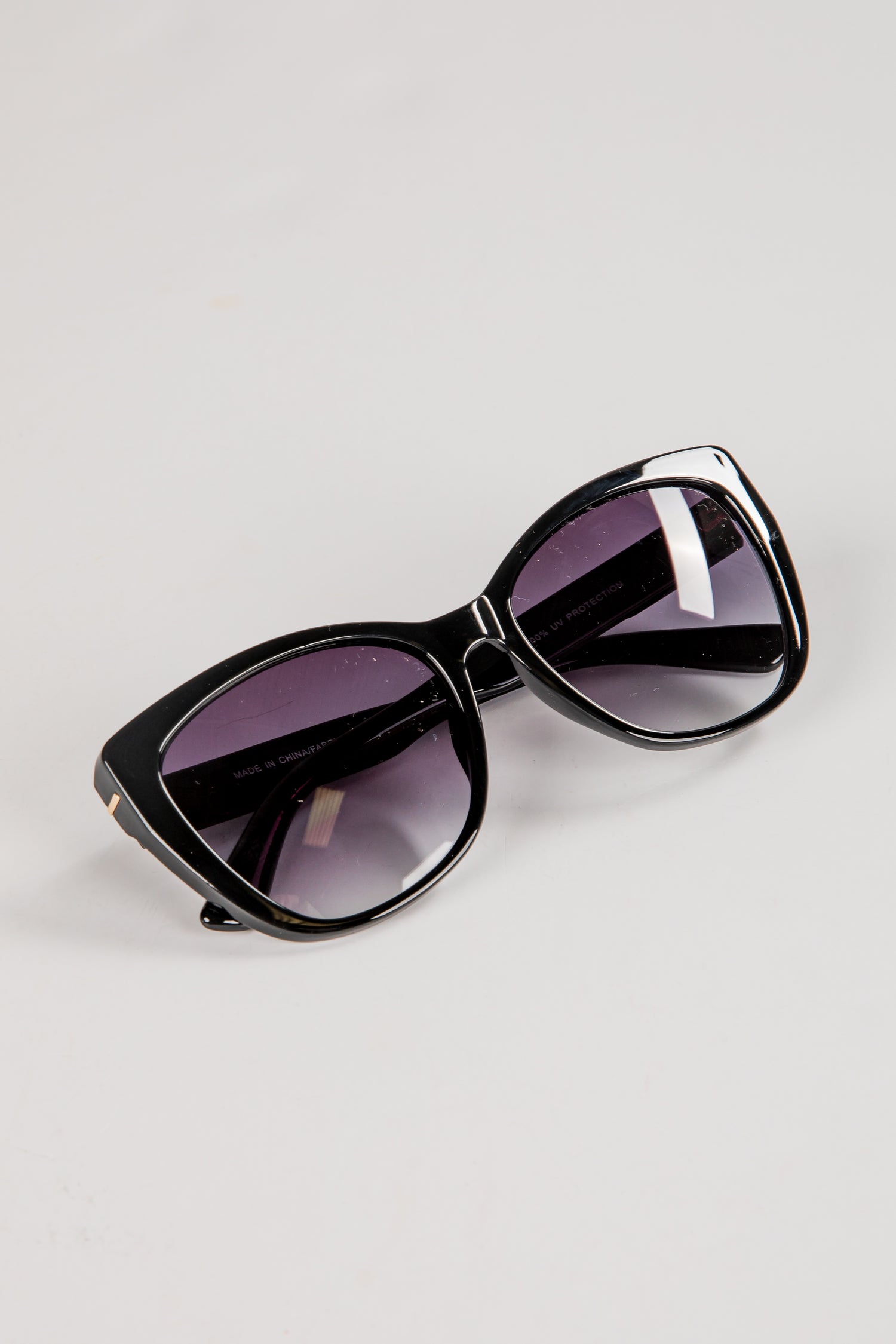 Black sunglasses with purple lenses on a light gray background