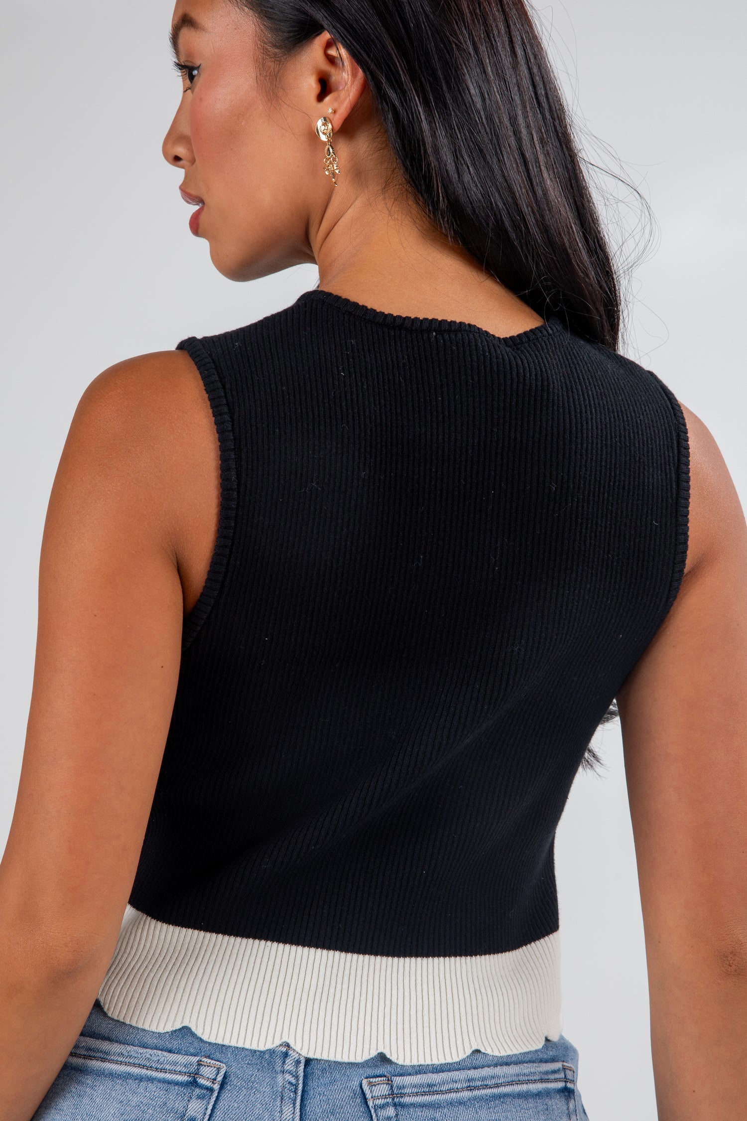 Woman wearing a black sleeveless top with a plain background