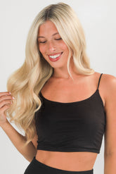 Woman wearing a black tank top against a plain background