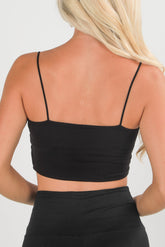 Black crop top worn by a person on a plain background