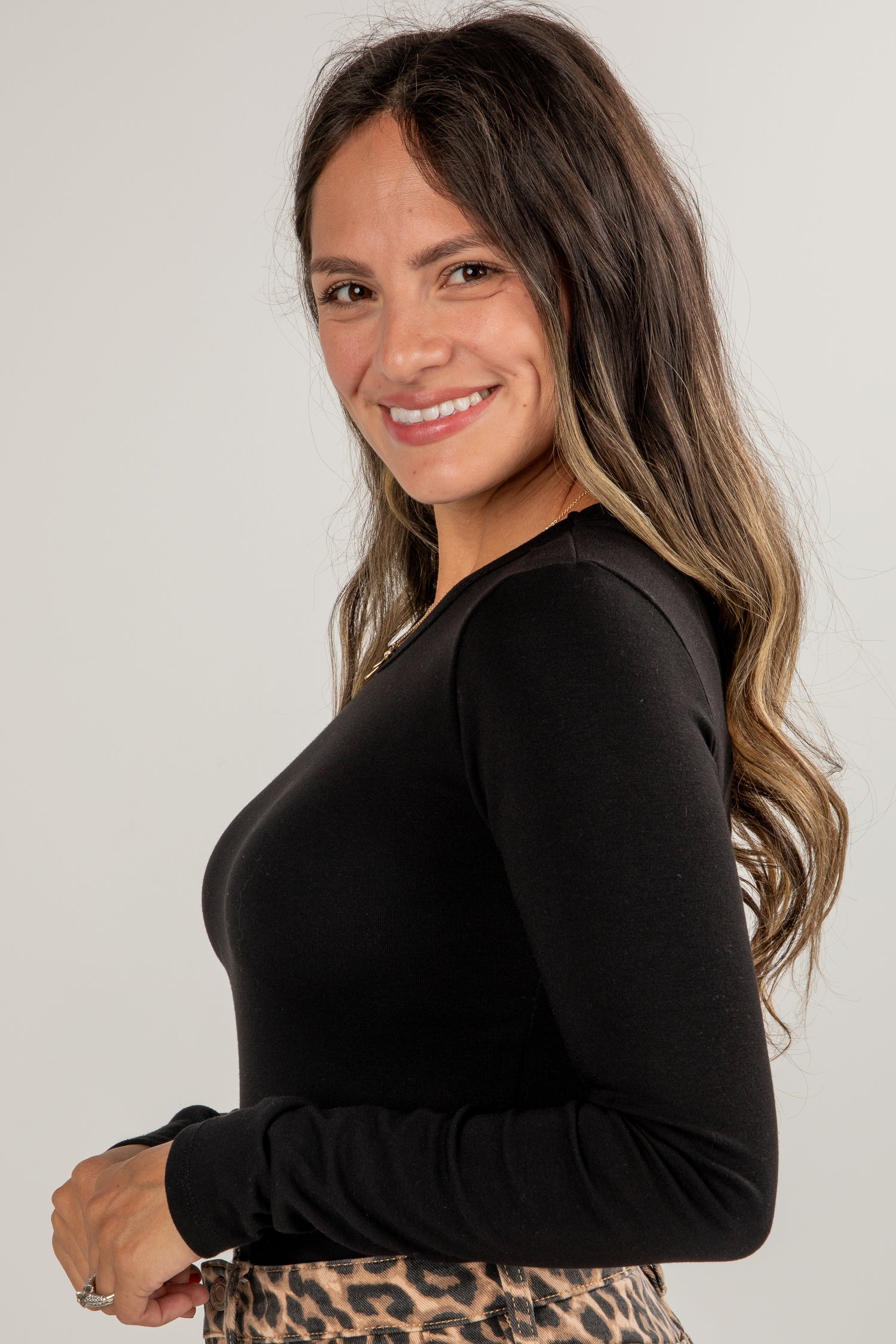Woman wearing a black long-sleeve top with a plain background