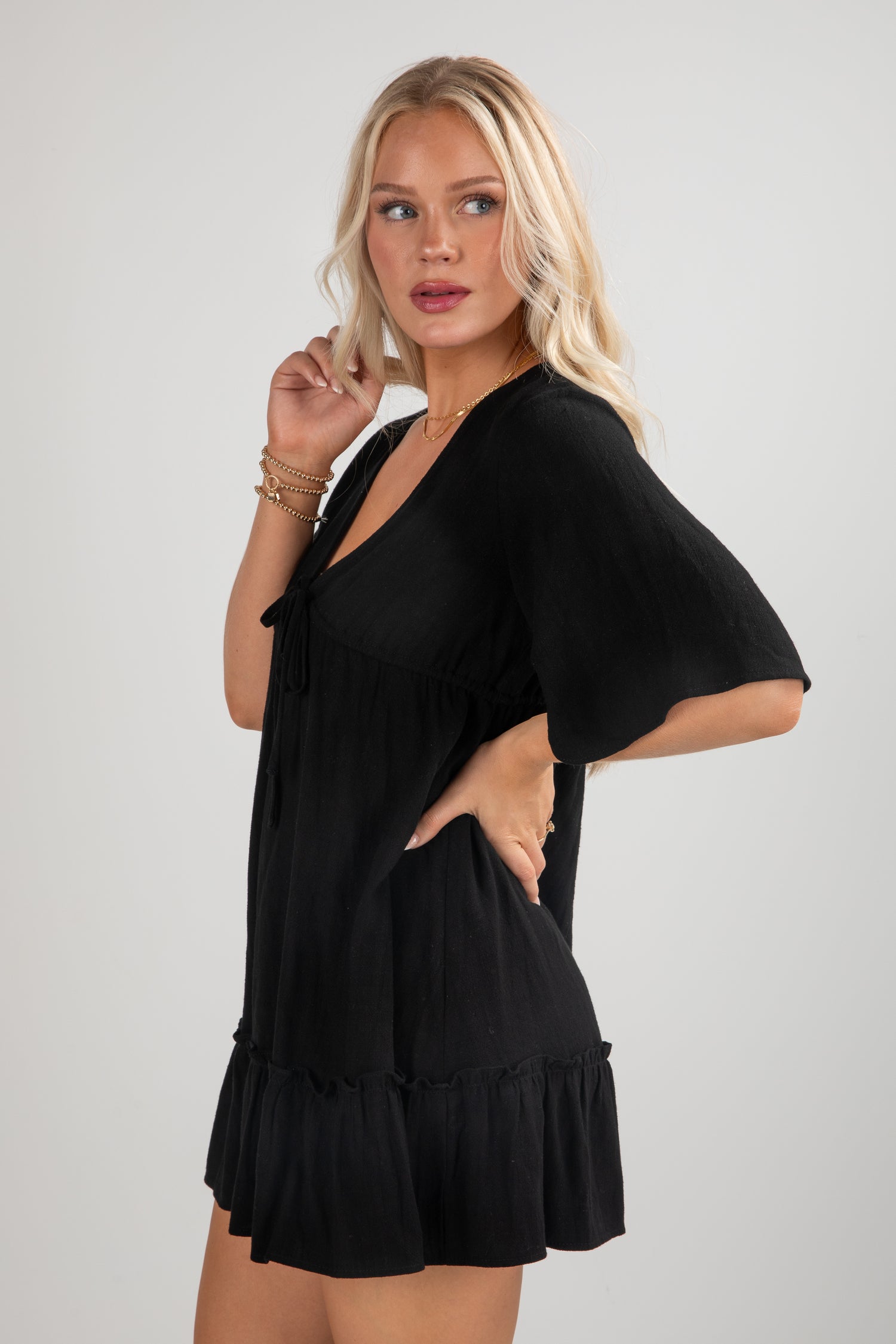 Woman wearing a black dress with ruffled hem on a light gray background