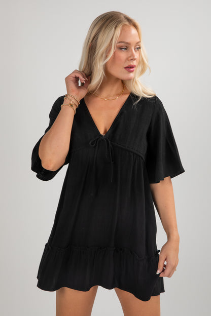 Woman wearing a black dress against a plain background