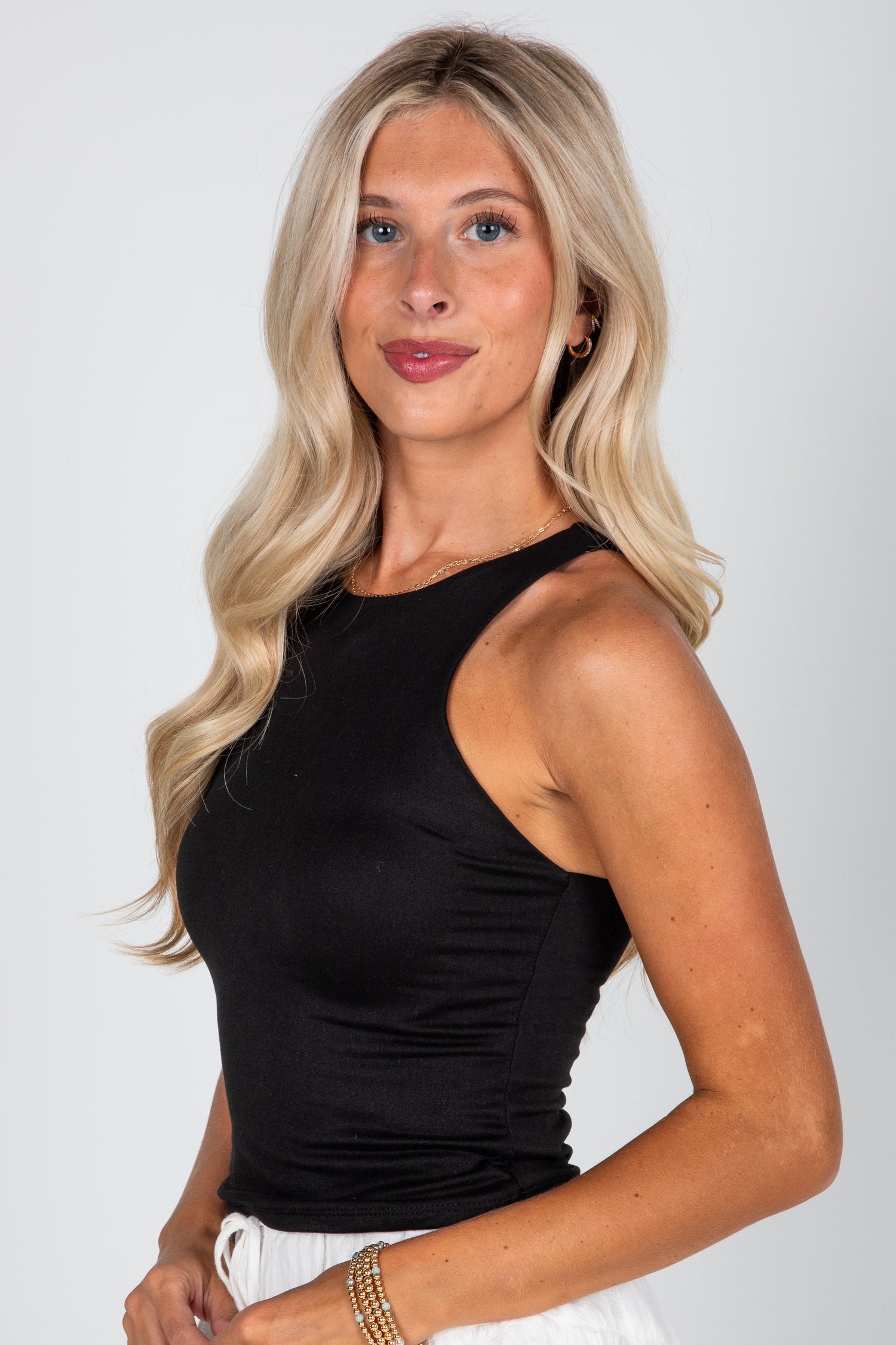 Woman wearing a black sleeveless top against a white background