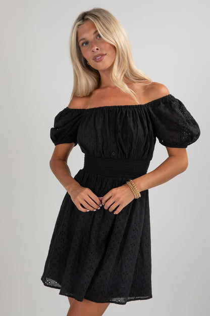 Woman wearing a black off-shoulder dress against a gray background