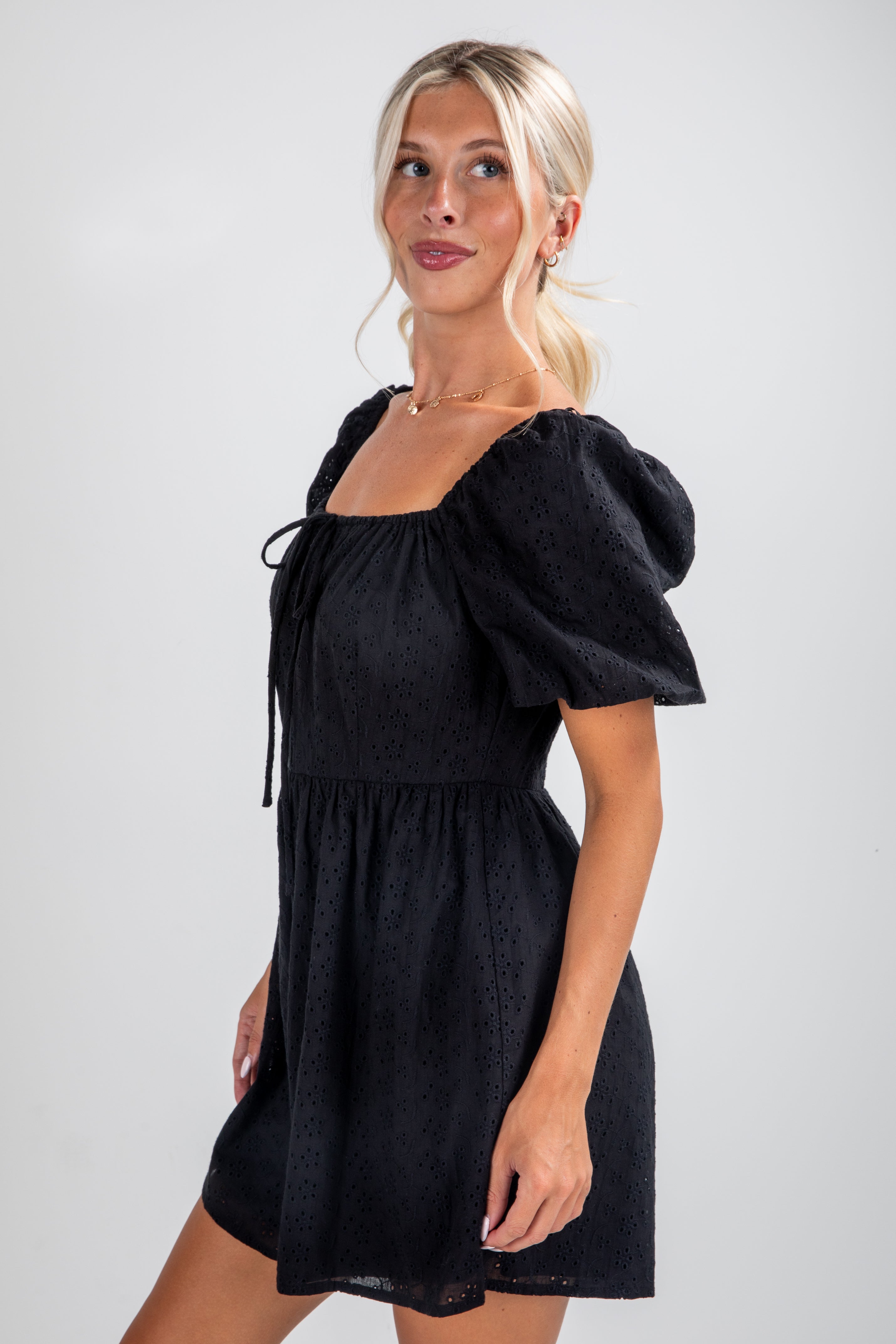 Woman wearing a black dress with puff sleeves on a white background