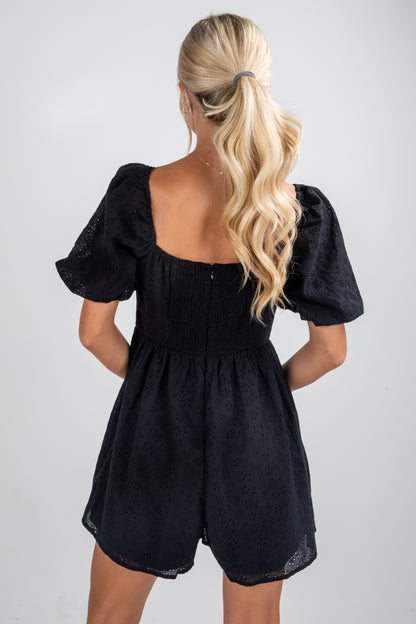 Black romper worn by a person with blonde hair on a plain background
