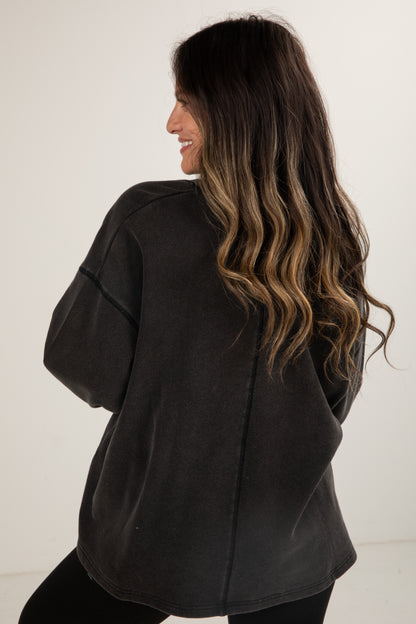 Woman wearing a black oversized sweater against a white background