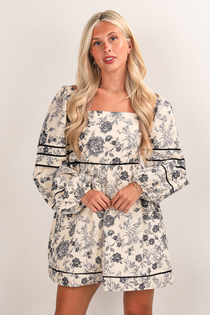 Woman wearing a floral dress with long sleeves on a plain background