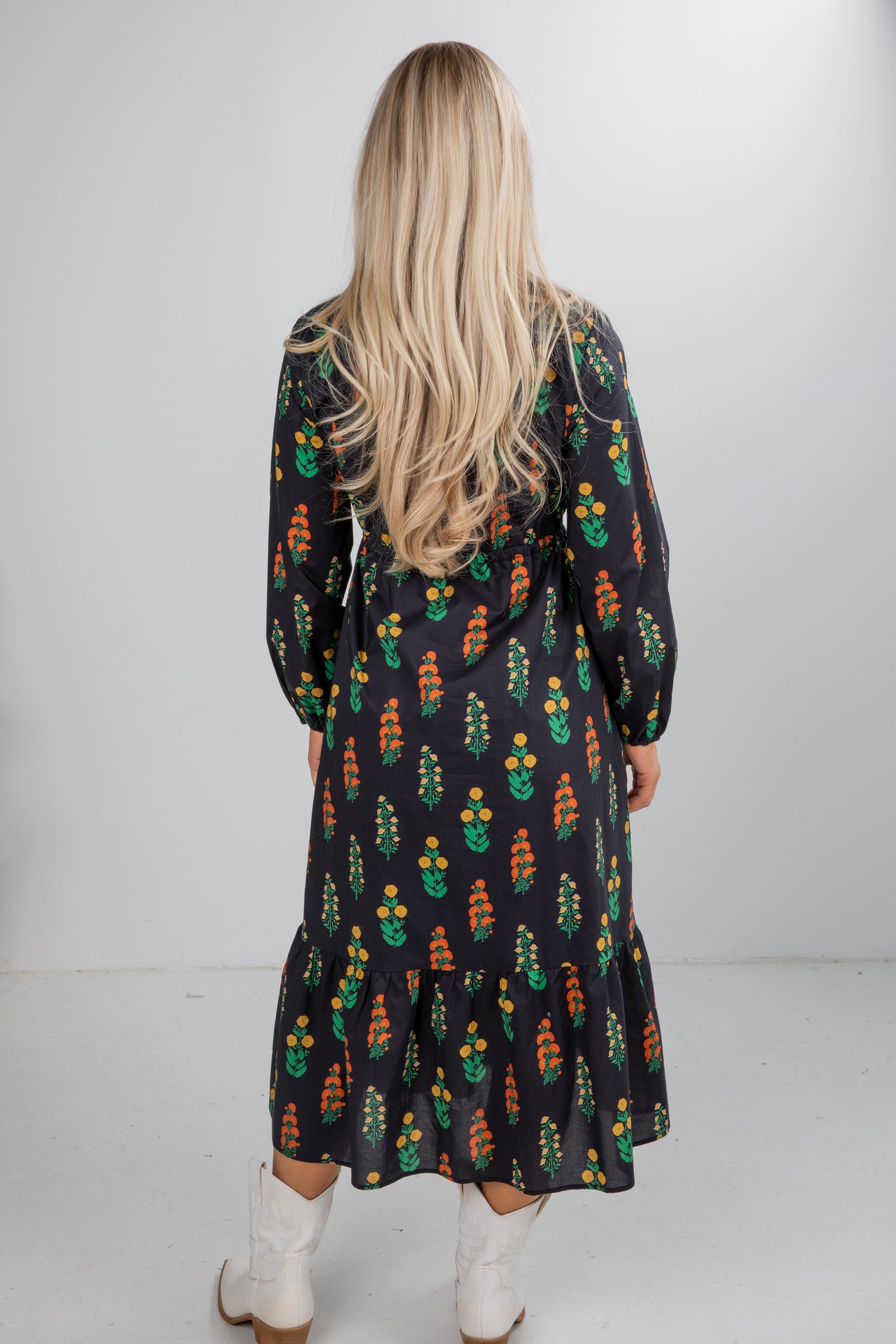 Person wearing a patterned dress with long sleeves and a white background