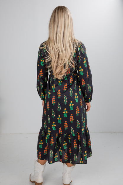 Person wearing a patterned dress with long sleeves and a white background