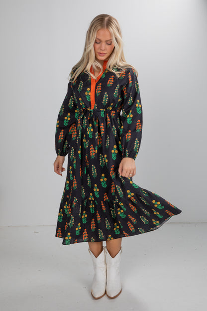 Woman wearing a long-sleeve dress with a colorful pattern on a white background