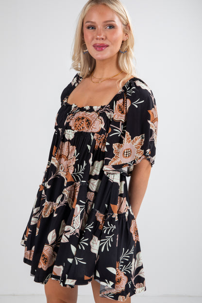 Woman wearing a black floral dress against a white background