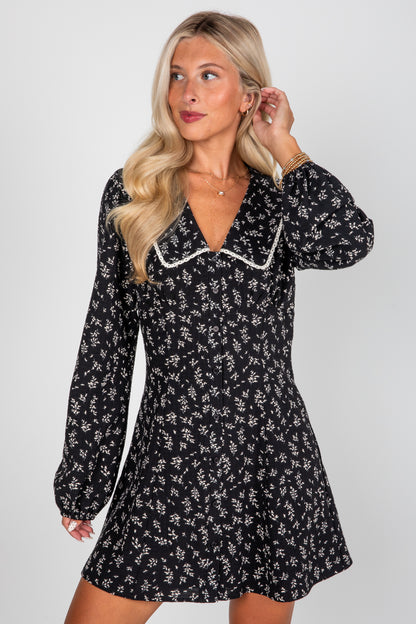 Woman wearing a black floral dress against a white background