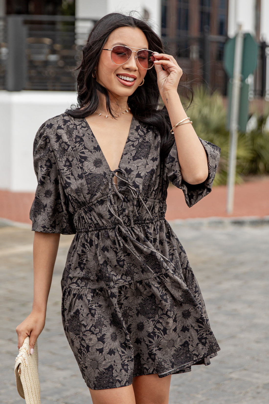 Woman wearing a floral dress and sunglasses outdoors.