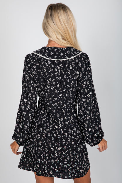 Person wearing a black floral dress against a white background