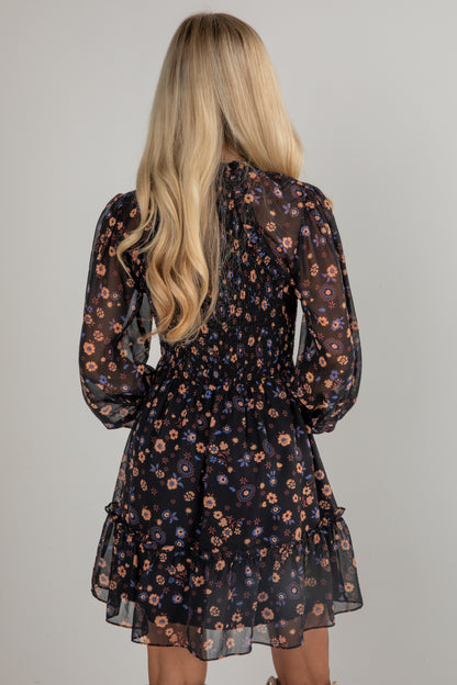 Woman wearing a floral dress with long sleeves on a plain background